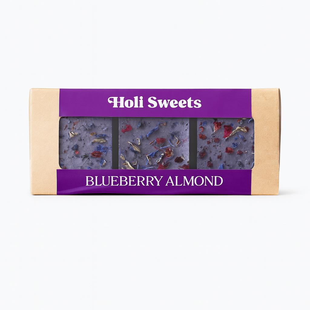 Holi Sweets Blueberry Almond vegan dessert box with three handmade, gluten-free, dairy-free blueberry bars topped with dried flowers and almonds in eco-friendly packaging – gourmet plant-based treat from Munich