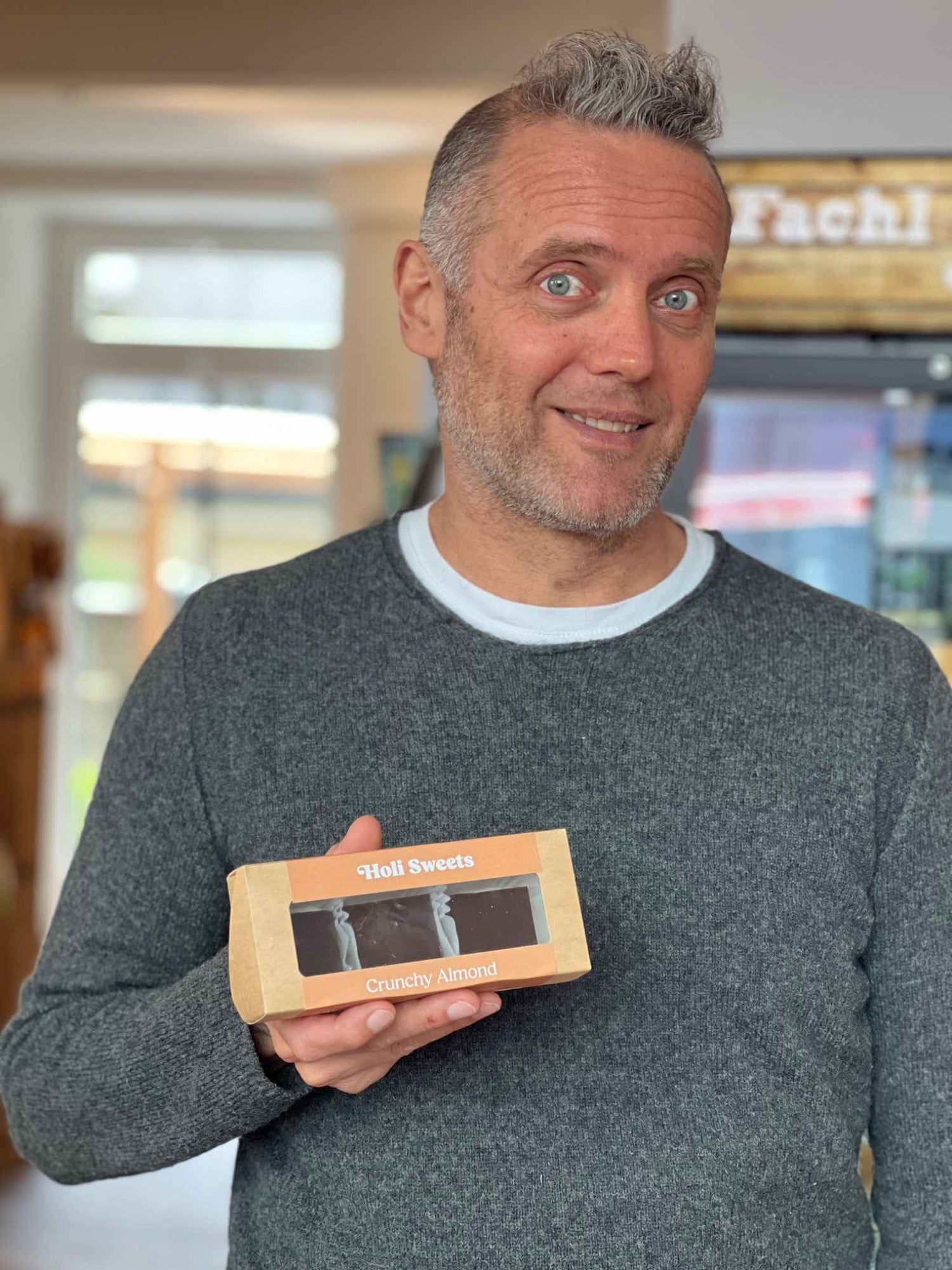 Michael Wirth hält eine Packung veganer Holi Sweets „Crunchy Almond“ im Laden in München.