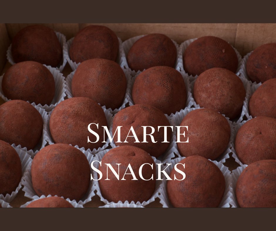 Handgemachte rohe Kakaotrüffel in Papierförmchen, ordentlich angeordnet in einer Schachtel, mit dem Text „Smarte Snacks“ darüber.