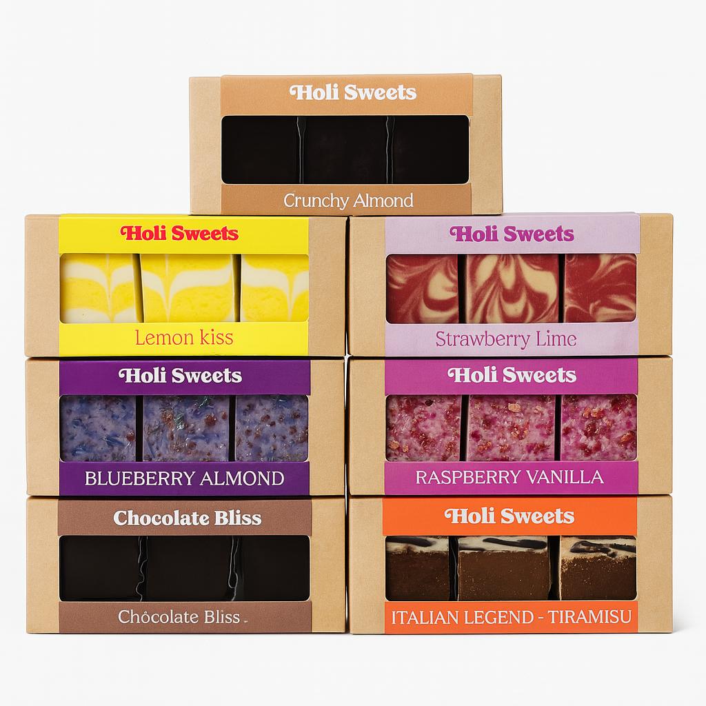 Sieben Holi Sweets vegane Dessertboxen in verschiedenen Sorten, darunter Lemon Kiss, Strawberry Lime, Raspberry Vanilla, Blueberry Almond, Chocolate Bliss, Crunchy Almond und Italian Legend Tiramisu – schön arrangierte, glutenfreie, laktosefreie und ohne raffinierten Zucker hergestellte Leckereien.