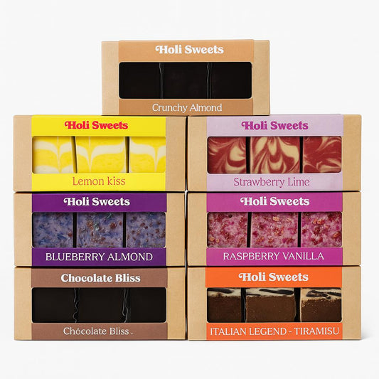 Sieben Holi Sweets vegane Dessertboxen in verschiedenen Sorten, darunter Lemon Kiss, Strawberry Lime, Raspberry Vanilla, Blueberry Almond, Chocolate Bliss, Crunchy Almond und Italian Legend Tiramisu – schön arrangierte, glutenfreie, laktosefreie und ohne raffinierten Zucker hergestellte Leckereien.