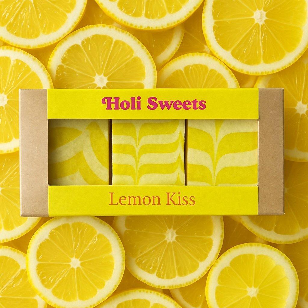 Rohveganer Zitronenkuchen Lemon Kiss – vegane glutenfreie Süßigkeit ohne Zucker in Geschenkverpackung, vor Zitronenhintergrund